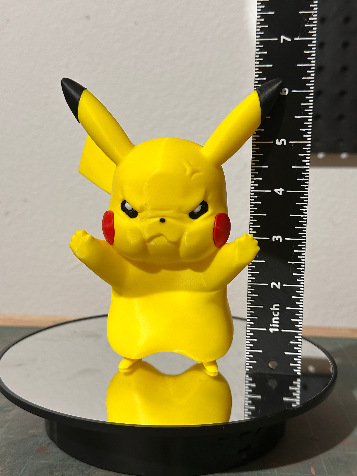Yellow Pikachu figurine next to a ruler on a gray background